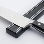 Soporte magnético para cuchillos con un cuchillo de acero inoxidable plateado con mango negro.