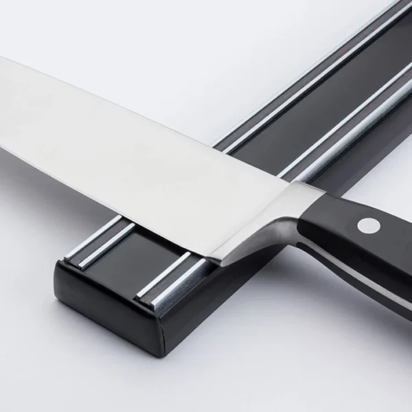 Soporte magnético para cuchillos con un cuchillo de acero inoxidable plateado con mango negro.
