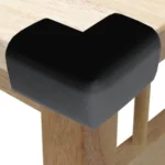 Esquinero protector negro en L para mesa de madera, ideal para seguridad infantil.