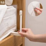 Sujetador de sábanas de cama blanco de plástico ajustando una sábana en un marco de madera.