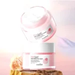 Crema Hidratante de Sal Rosa Hima, reafirma y humecta, en envase rosa y blanco sobre rocas y flor.
