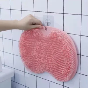 Tapete de baño rosa con ventosas antideslizantes, colgando de un gancho en una pared de azulejos.
