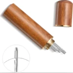 Agujas de coser autoenhebrables en estuche cilíndrico de madera con tapa dorada.