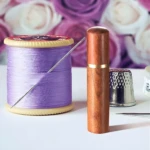 Agujas de coser autoenhebrables con carrete de hilo púrpura y dedal.