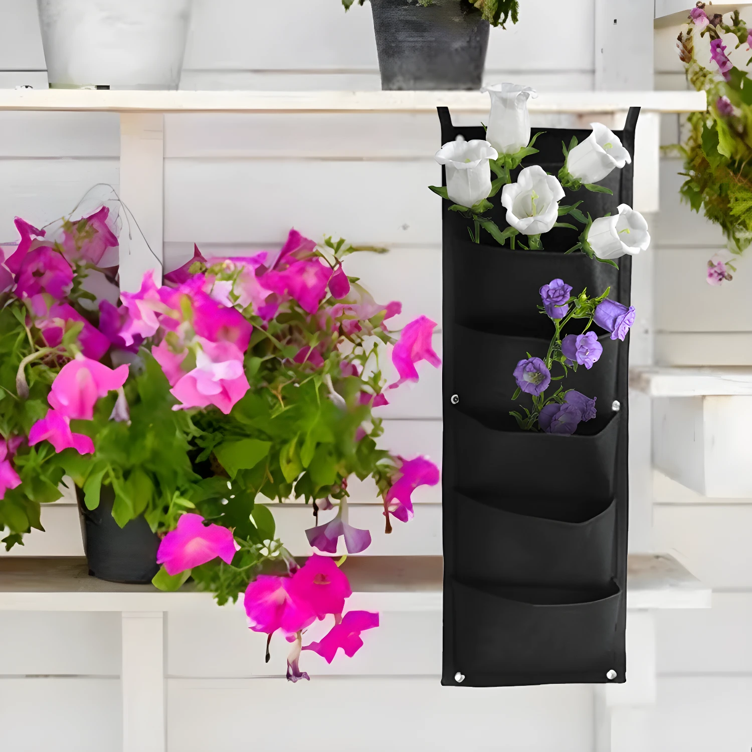 Bolsa para plantar vertical negra con flores blancas y moradas.