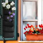 Bolsa para plantar vertical con flores blancas y moradas en pared, junto a ventana con tulipanes en maceta.