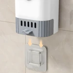 Cepillo de baño blanco y gris colgado en pared de baldosín claro con soporte transparente.