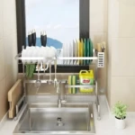 Escurridor de loza de 64 cm sobre lavaplatos, con platos, cubiertos y accesorios organizados.