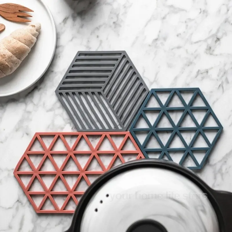 Juego de 4 posavasos hexagonales de silicona, gris, azul y coral, sobre mármol.