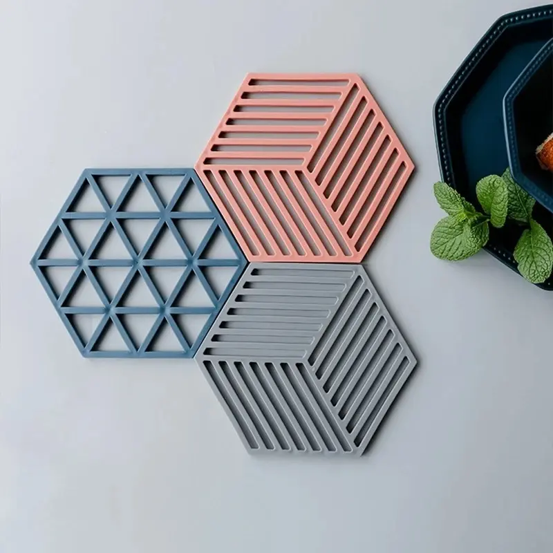 Set de 4 posavasos de silicona hexagonales en tonos azul, rosa y gris con diseños geométricos.