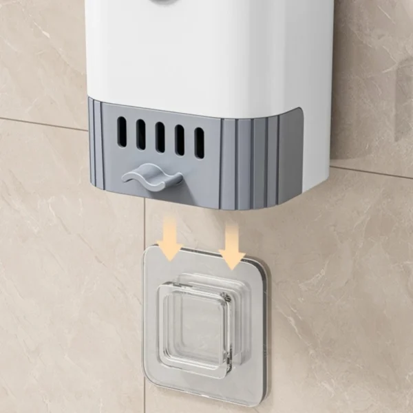 Cepillo de baño blanco y gris colgando en pared con gancho adhesivo transparente.