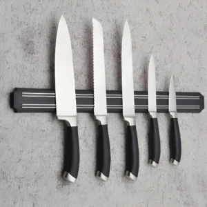 Set de 6 cuchillos de cocina con mango negro y soporte magnético en pared gris.