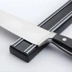 Soporte magnético negro para cuchillos con cuchillo de chef metálico y mango negro.