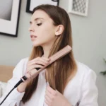 Plancha de cabello Remington Keratin Therapy alisando el cabello castaño de una mujer joven.