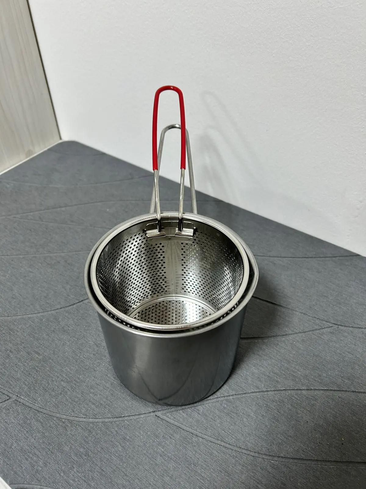 Olla freidora con escurridor de aceite, de acero inoxidable, con asas rojas, diseño perforado para cocina.