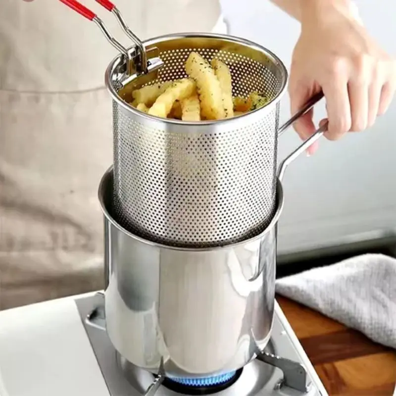 Olla freidora con escurridor de aceite, friendo papas doradas en sartén sobre estufa.