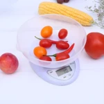 Gramera digital con recipiente, mostrando tomates, chiles y durazno, ideal para pesar ingredientes.