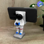 Base celular astronauta Sancafé con celular negro, ideal para escritorio.