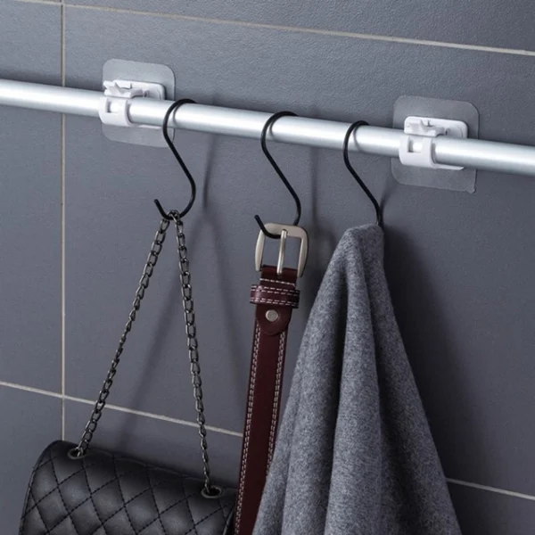 Barra ajustable para cortina sin clavos sosteniendo bolso, cinturón y toalla de gris.