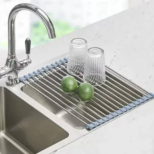 Escurridor enrollable de acero inoxidable para secar platos sobre el lavaplatos, con limones y vasos.