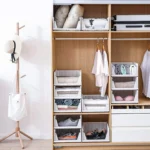 Organizador de armario apilable con cestas blancas, ropa y zapatos organizados.