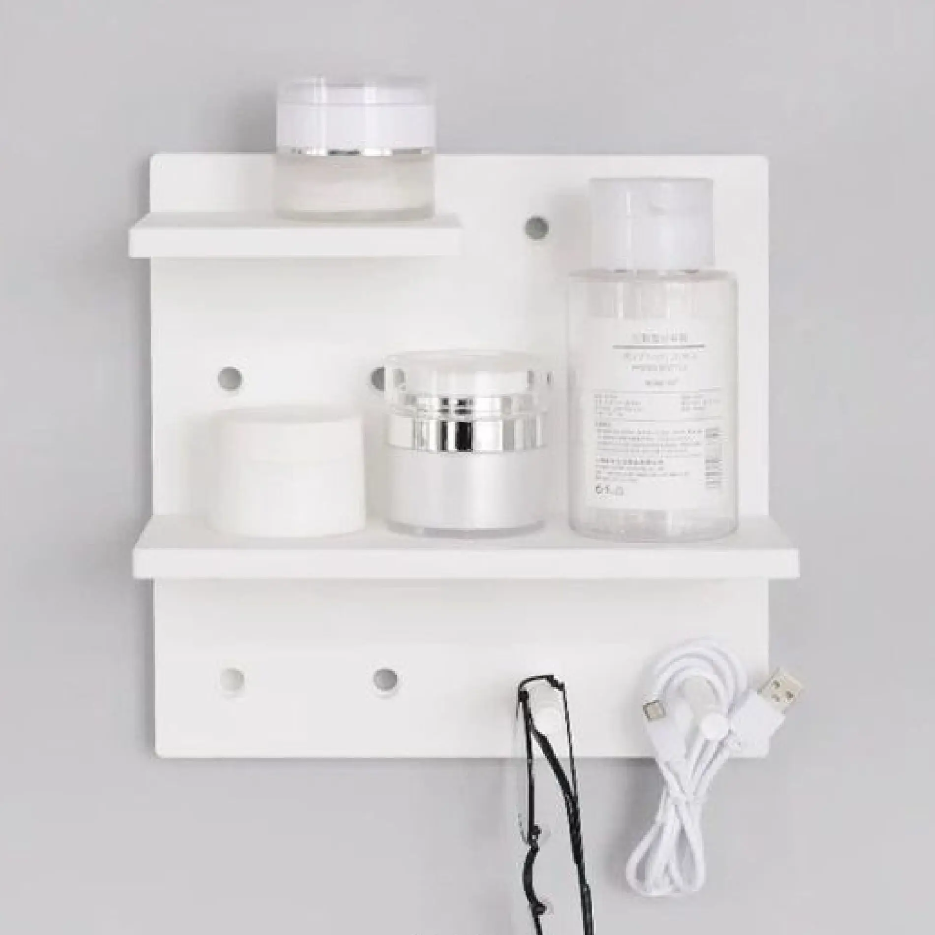 Repisa organizador blanco perforado con frascos de crema y cable USB.