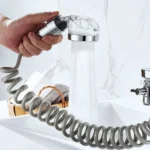 Extensor de grifo con rociador portátil y manguera en espiral gris, ideal para baño o cocina.
