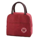 Lonchera térmica roja con asas marrones y parche de panda, ideal para almuerzos.