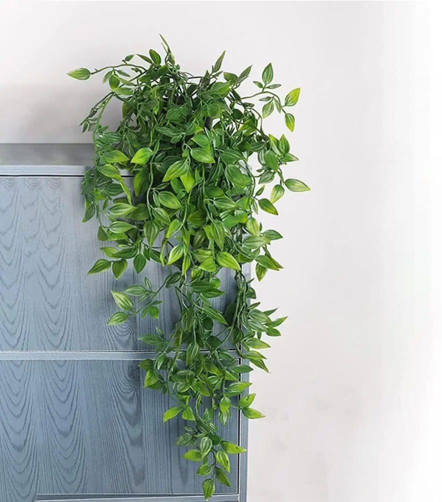 Planta colgante hiedra artificial verde sobre matero gris, decoración colgante.