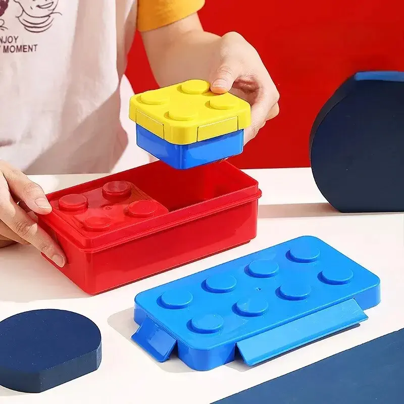 Fiambrera lonchera estilo Lego colorida: caja roja, tapa azul y amarilla, y otra pieza azul con "botones".