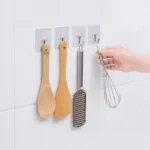Cepillos de cocina de madera y rallador colgando en ganchos adhesivos.