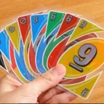 Mano sosteniendo cartas de juego Uno H2O con números 9 y 6 visibles.
