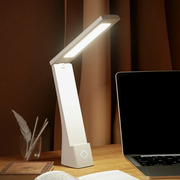 Lámpara de escritorio LED recargable, blanca, con laptop y libros.