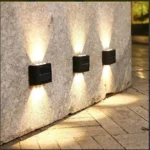 Lámpara solar aplique 6 LED ilumina pared de piedra y sendero con luz cálida.