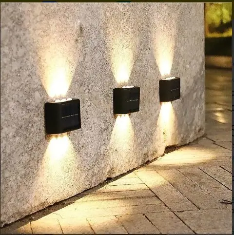 Lámpara solar aplique 6 LED ilumina pared de piedra y sendero con luz cálida.
