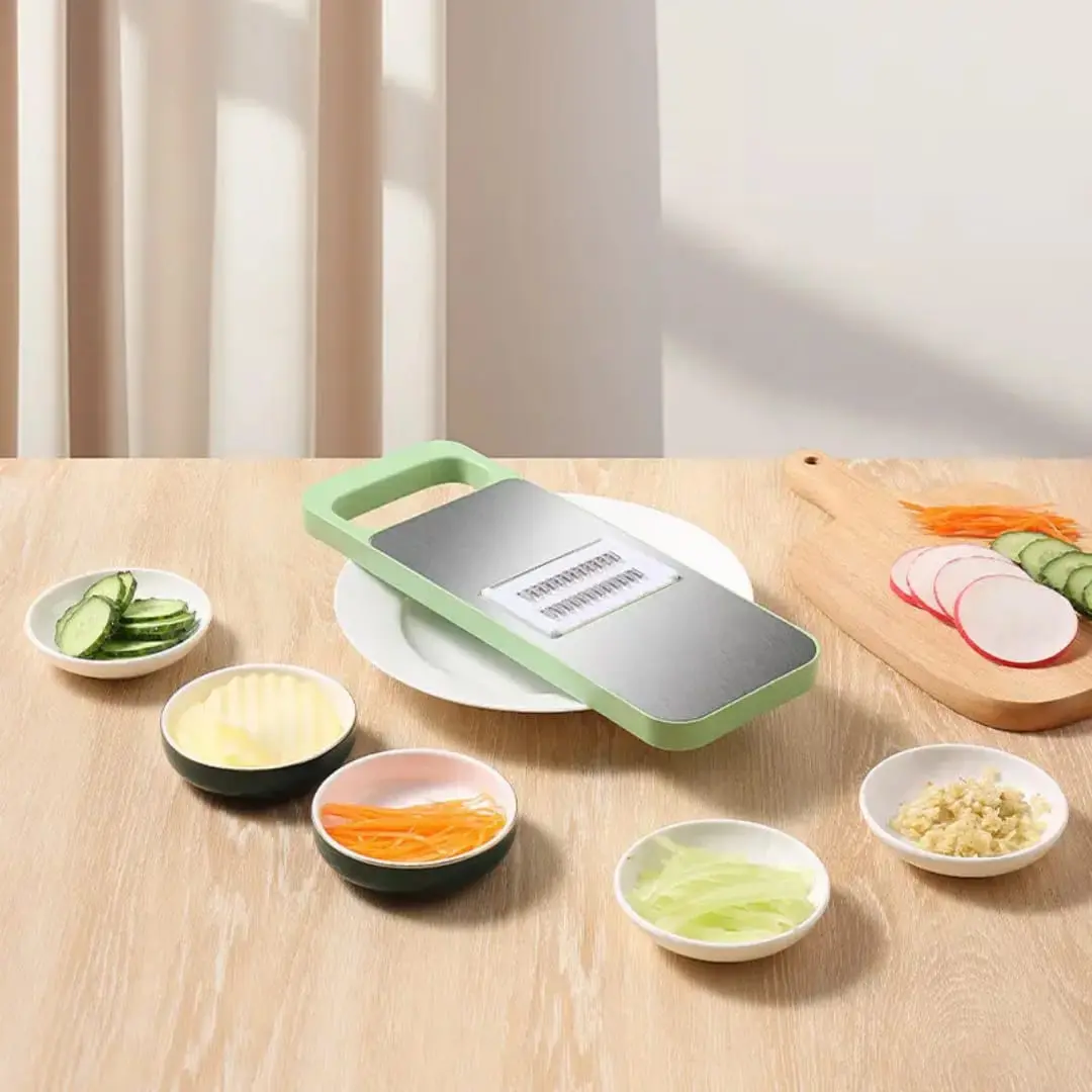 Picatodo para vegetales con cortador de acero inoxidable y recipientes con rodajas de pepino, zanahoria y rábano.