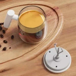 Taza mezcladora eléctrica de café con asa blanca sobre bandeja de madera.