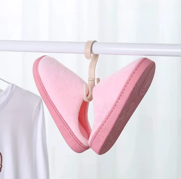 Gancho giratorio para colgar pantuflas rosadas y ropa blanca en perchero.