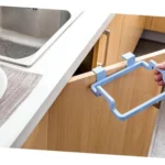 Soporte colgante azul para bolsa de basura sobre puerta de gabinete de cocina.