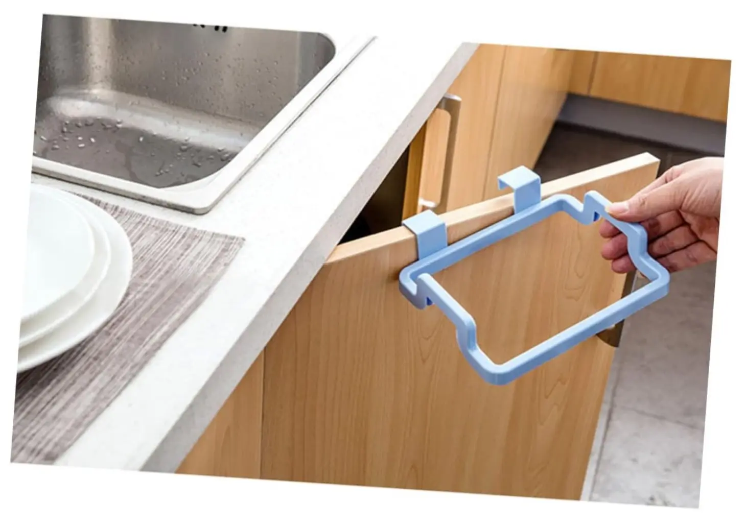 Soporte colgante azul para bolsa de basura sobre puerta de gabinete de cocina.