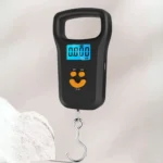 Balanza digital de equipaje con gancho, pantalla LCD azul brillante y diseño de carita sonriente.