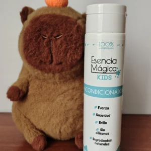 Acondicionador Esencia Mágica Kids 375ml con un peluche de mono junto a la botella sobre mesa de madera.