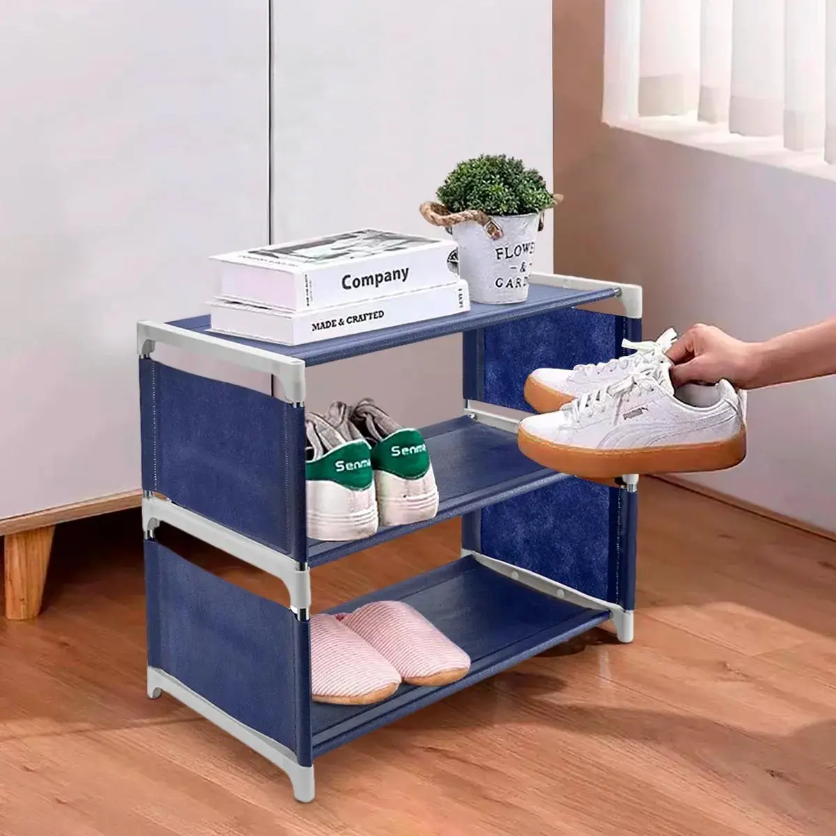 Organizador de zapatos 3 niveles azul con zapatillas, libros y planta.