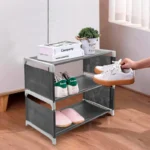 Zapatero organizador de 3 niveles gris con tenis blancos y pantuflas rosas.