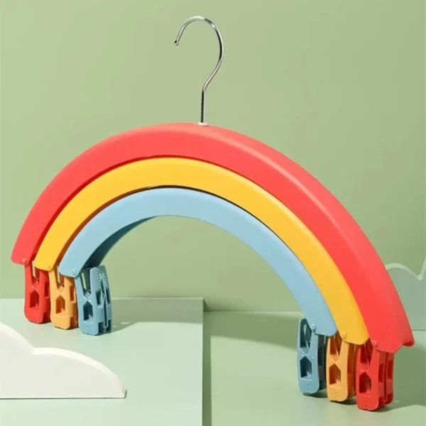 Colgador de ropa en forma de arcoíris con pinzas para secar, ideal para organizar prendas.