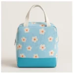 Bolsa lonchera térmica azul con flores blancas y naranjas, ideal para almuerzos.