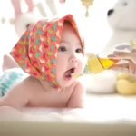 Bebé con pañuelo colorido recibe papilla de cuchara biberón, ideal para alimentación.