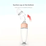 Cuchara biberón para papillas de bebé con tapa levadiza y base succionadora.