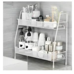 Estante organizador blanco de 2 niveles para baño, con botellas de jabón, cremas y difusor.