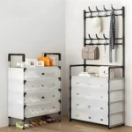 Estante organizador de zapatos y cajones blanco con perchero negro colgando ropa y bolsos.